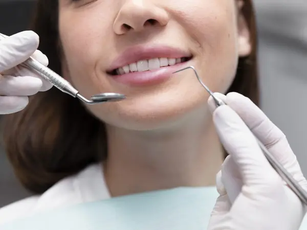 Dentista revisando los dientes de una paciente sonriente